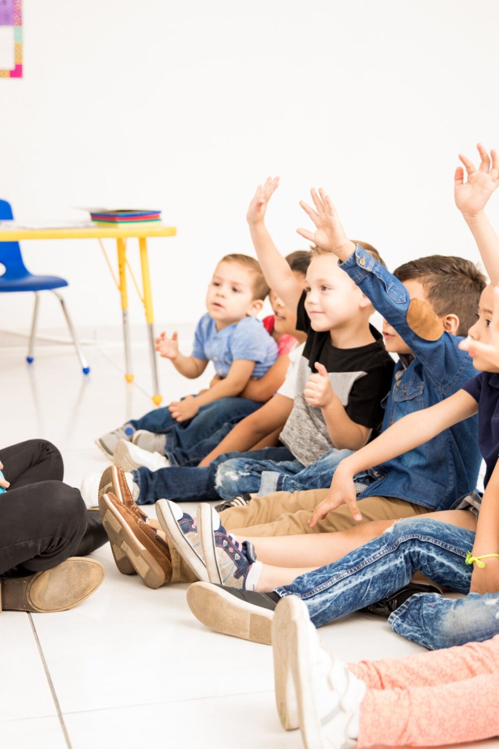 Preschool students raising their hands Profile view of a group of preschool students raising their hands and trying to participate at school